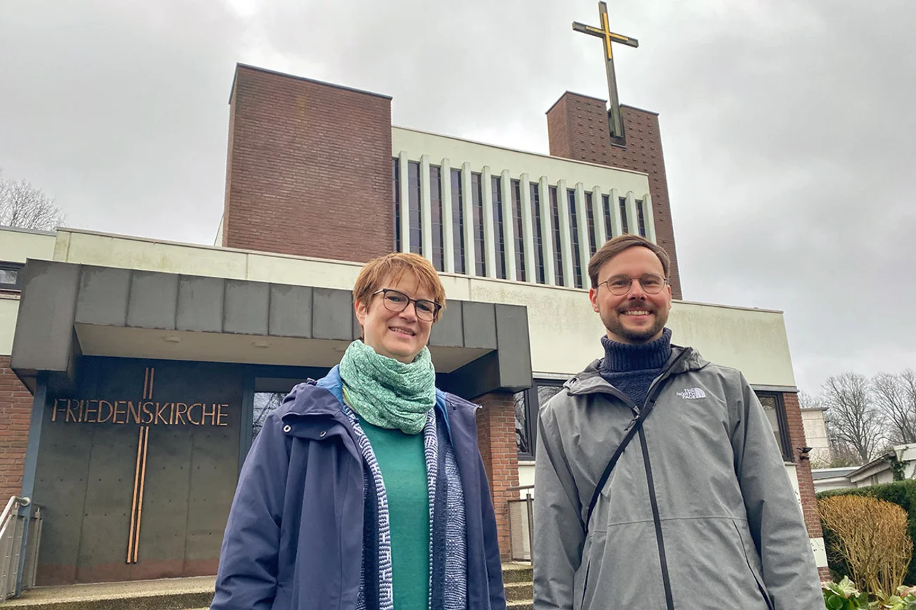 Ein Mann und eine Frau stehen vor einer Kirche. 