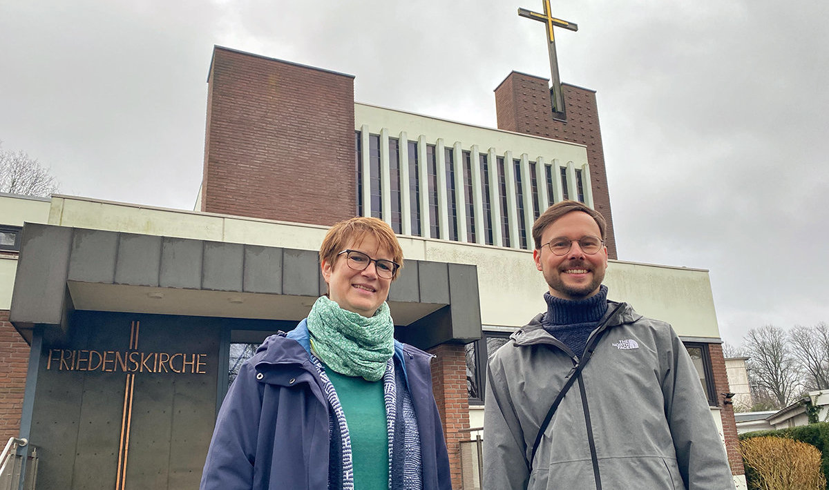 Ein Mann und eine Frau stehen vor einer Kirche. 