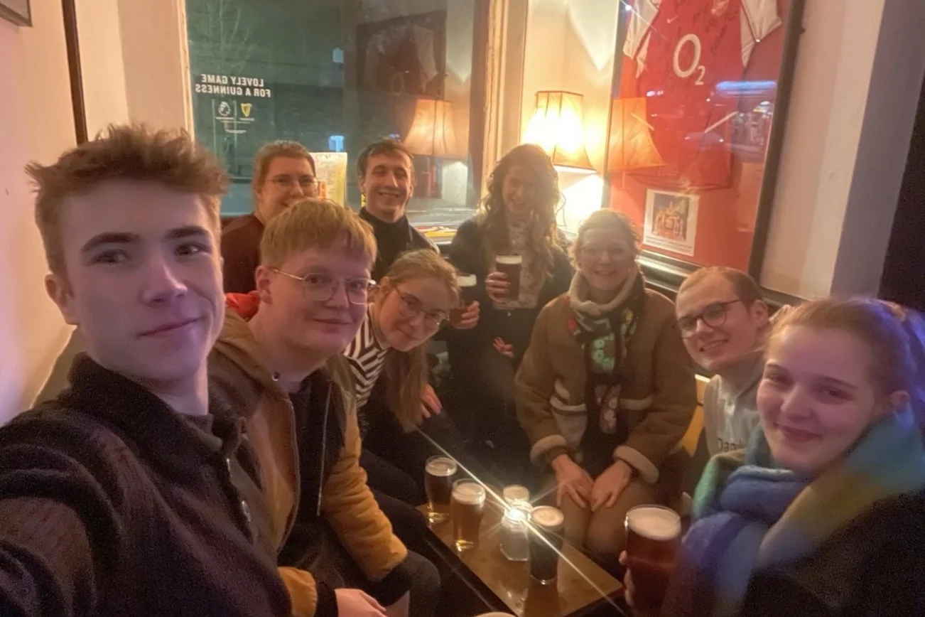 Selfie von vielen jungen Leuten an einem Tisch in einem Pub.