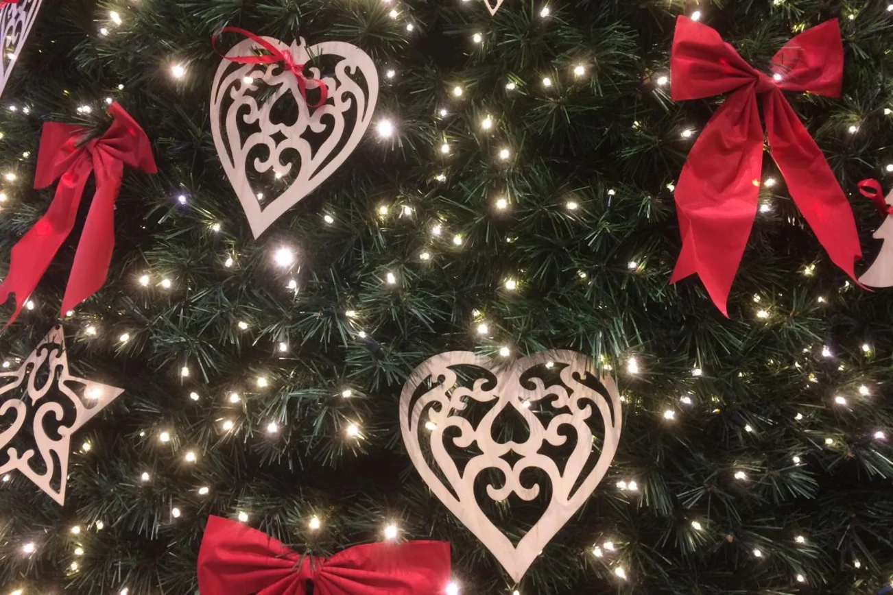 Herzen und Schleifen an Tannenbaum mit kleinen Lichtern. 