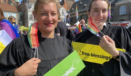 Zwei Personen stehen lächelnd auf dem Markt in Lübeck beim CSD. 