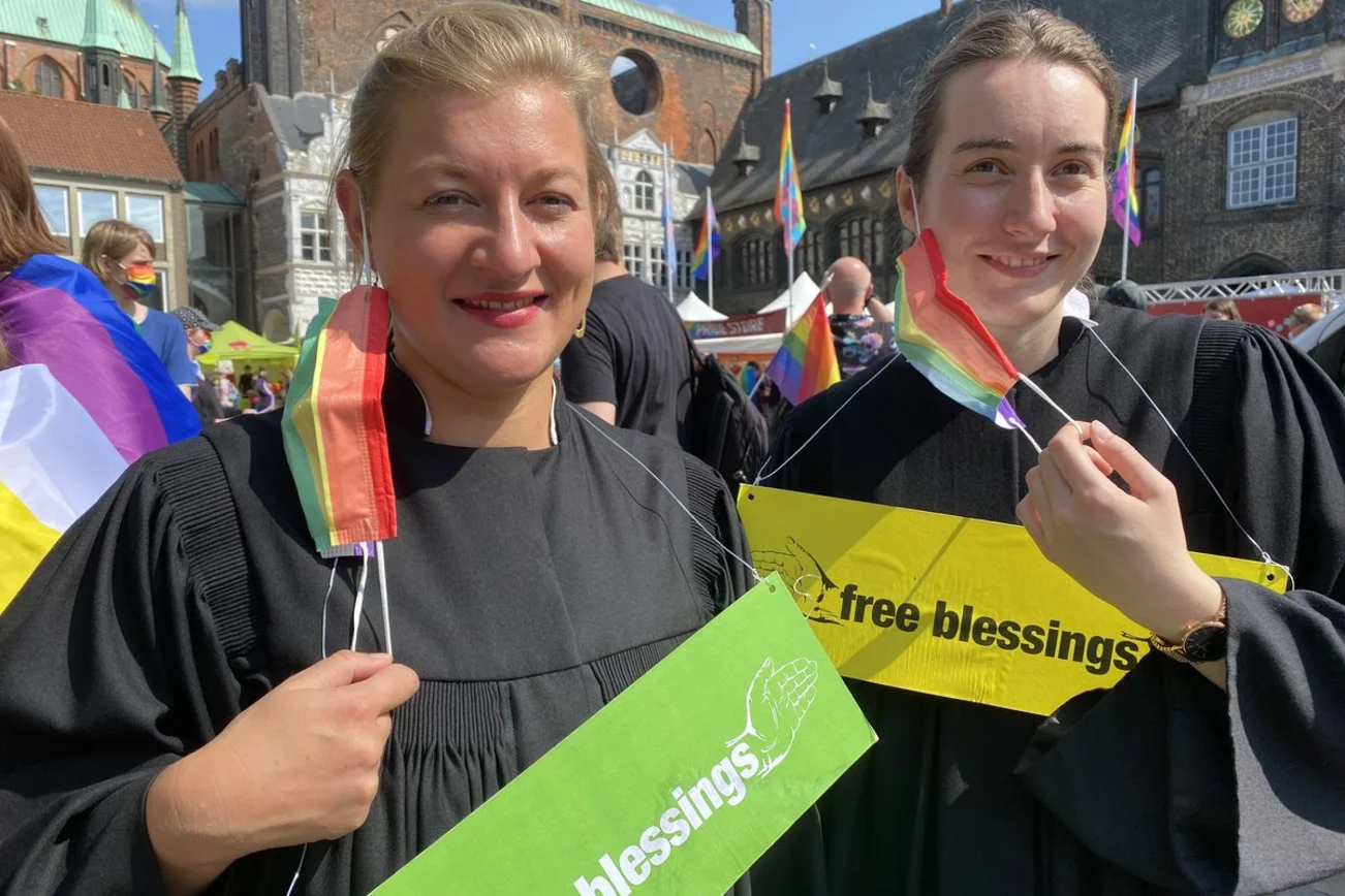 Zwei Personen stehen lächelnd auf dem Markt in Lübeck beim CSD. 