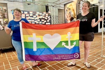 Zwei menschen mit einer bunten Flagge stehen lächelnd in einer Kirche.  - Copyright: Bastian Modrow