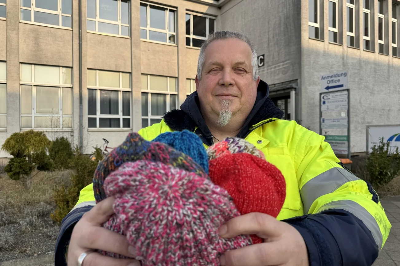 Ein Mann hält Mützen in der Hand 