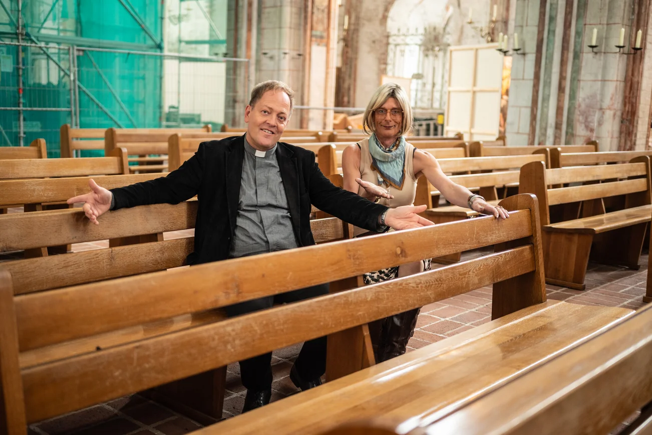 Ein Mann und eine Frau sitzen auf Kirchenbänken