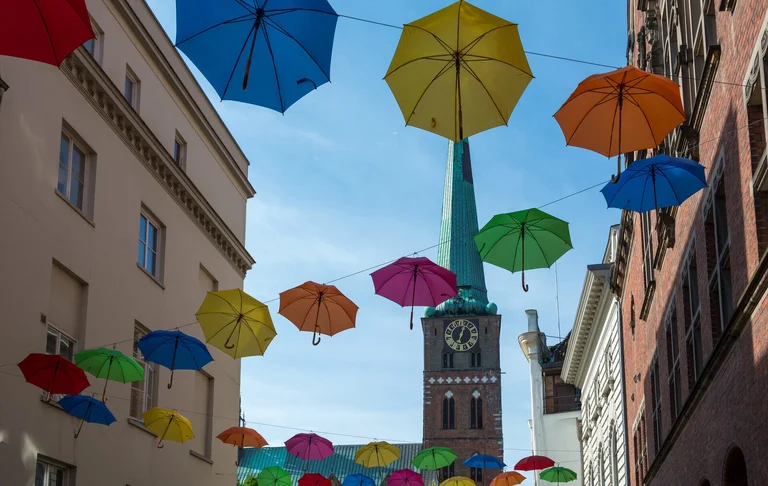 Aufgespannte Regenschirme in verschiedenen Farben, an mehreren Seilen aufgehängt - Im Hintergrund St. Jakobi Lübeck