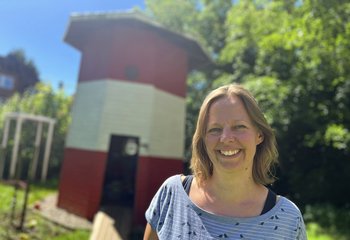 Eine Frau mit blonden Haaren steht vor einem Leuchtturm aus Holz in einem Garten. - Copyright: Annkathrin Bornholdt