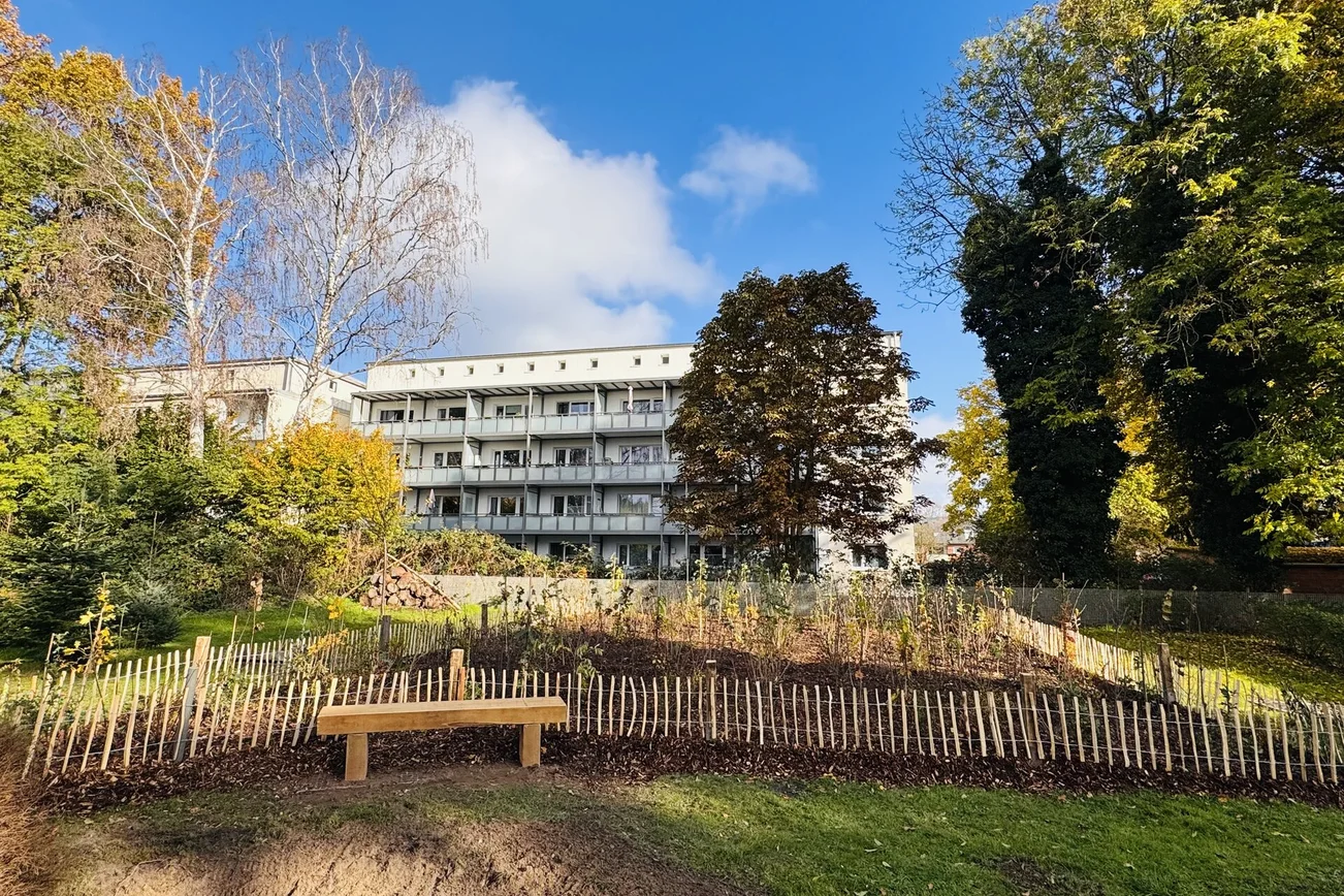 Blick auf eine Grünfläche vor einem mehrstöckigen Gebäude.