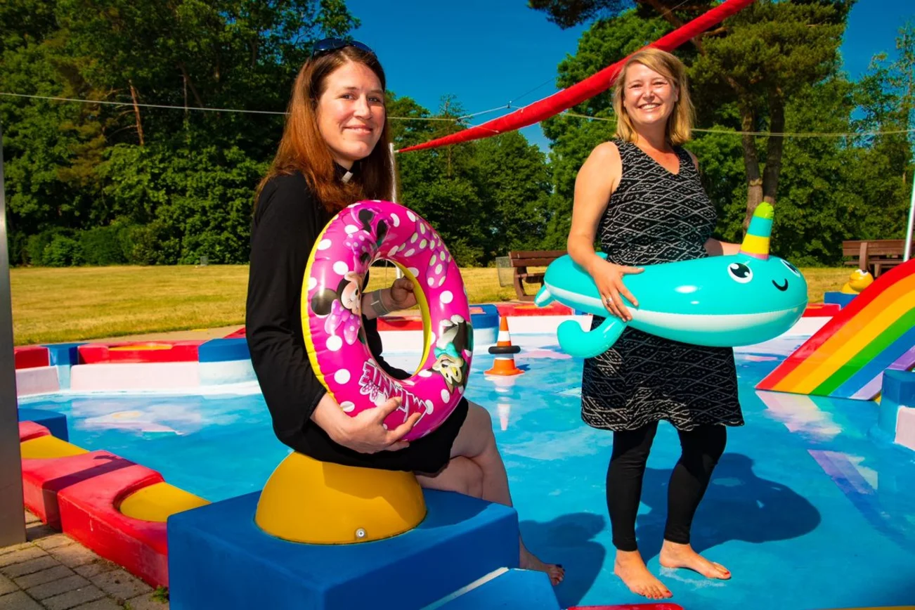 Zwei Frauen am Freibadbeckenrand mit aufblasbaren Gummitieren in der Hand.