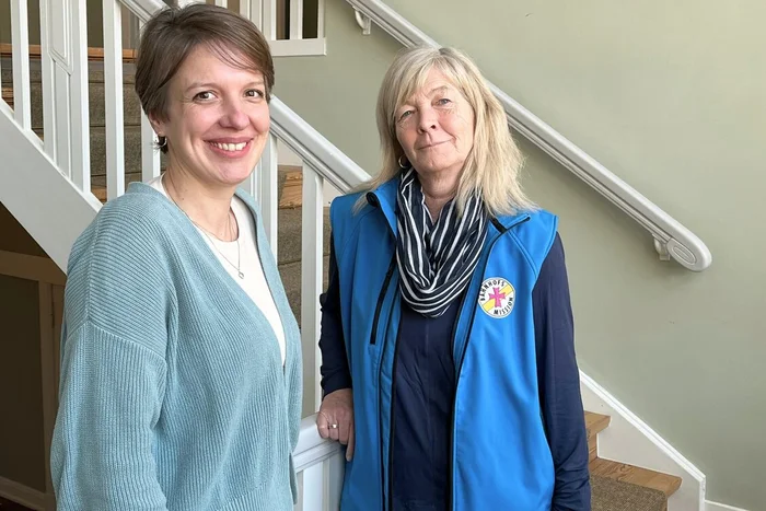 Zwei Frauen stehen vor einer Treppe.