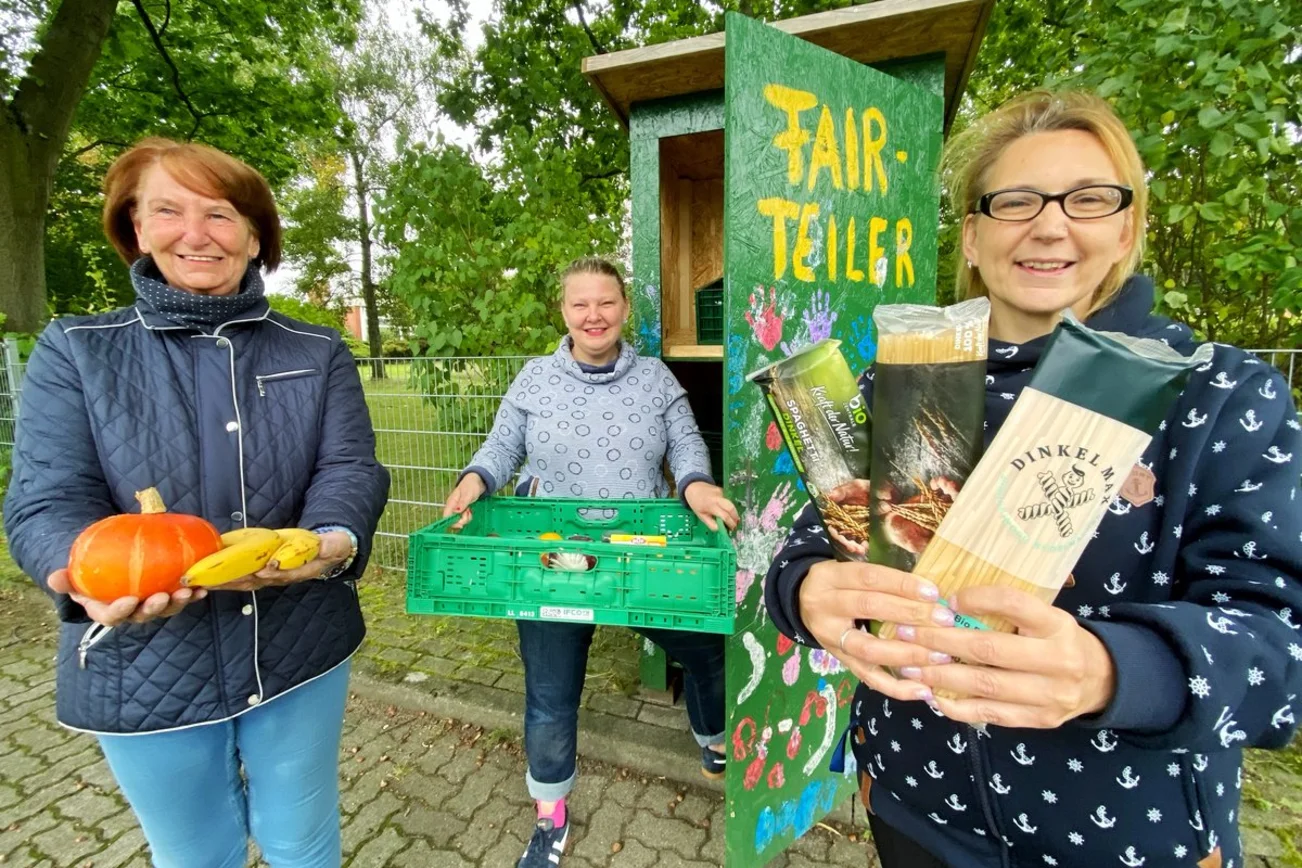 Drei Frauen stehen vor einem Fairteiler. 