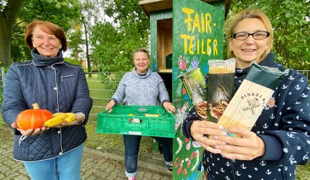 Drei Frauen stehen vor einem Fairteiler. 