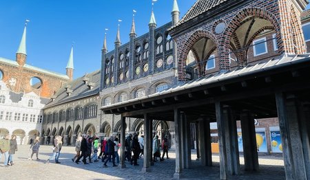 Der Pranger (Kaak) auf dem Rathausmarkt Lübeck, blauer Himmel und gehende Menschen