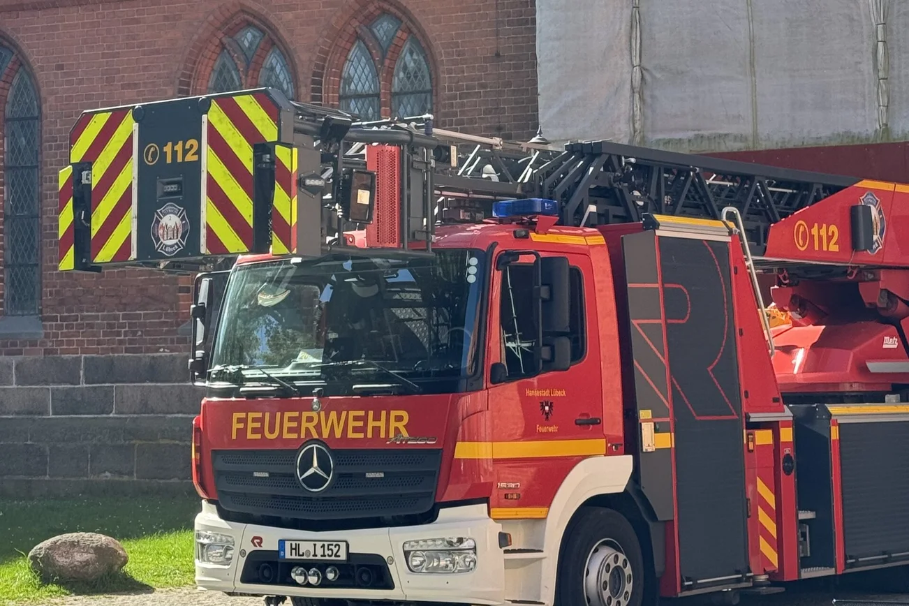 Ein Feuerwehr Löschzug steht vor einem alten Kirchengebäude.