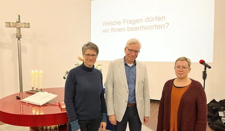 Drei Personen stehen in einer Kirche