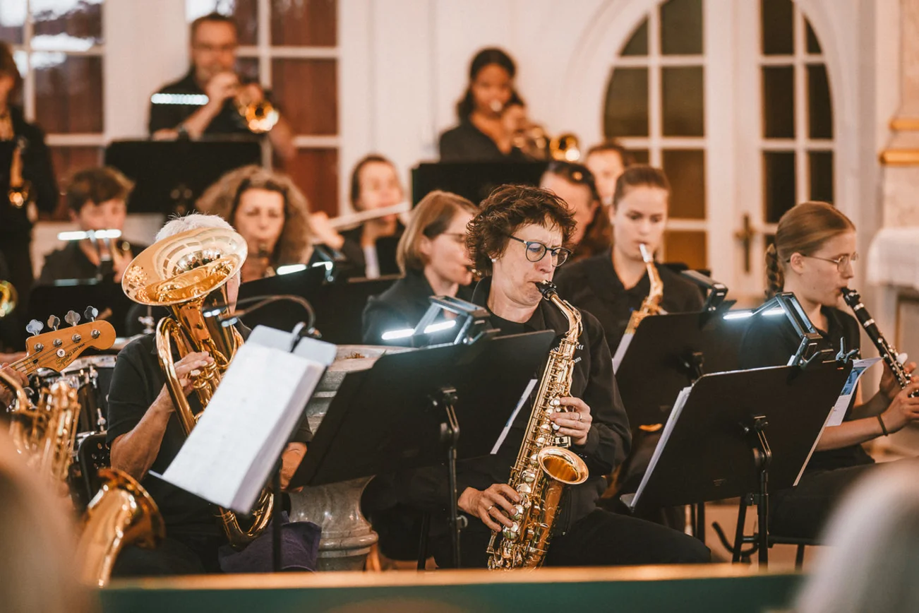 Mehrere Menschen blasen in ihr Saxophon.