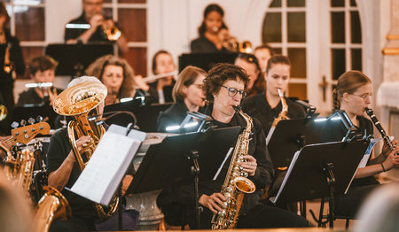 Mehrere Menschen blasen in ihr Saxophon.