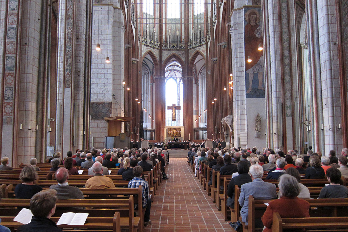 Gottesdienstbesucher sitzen auf Holzbänken in der St.-Marien-Kirche. 