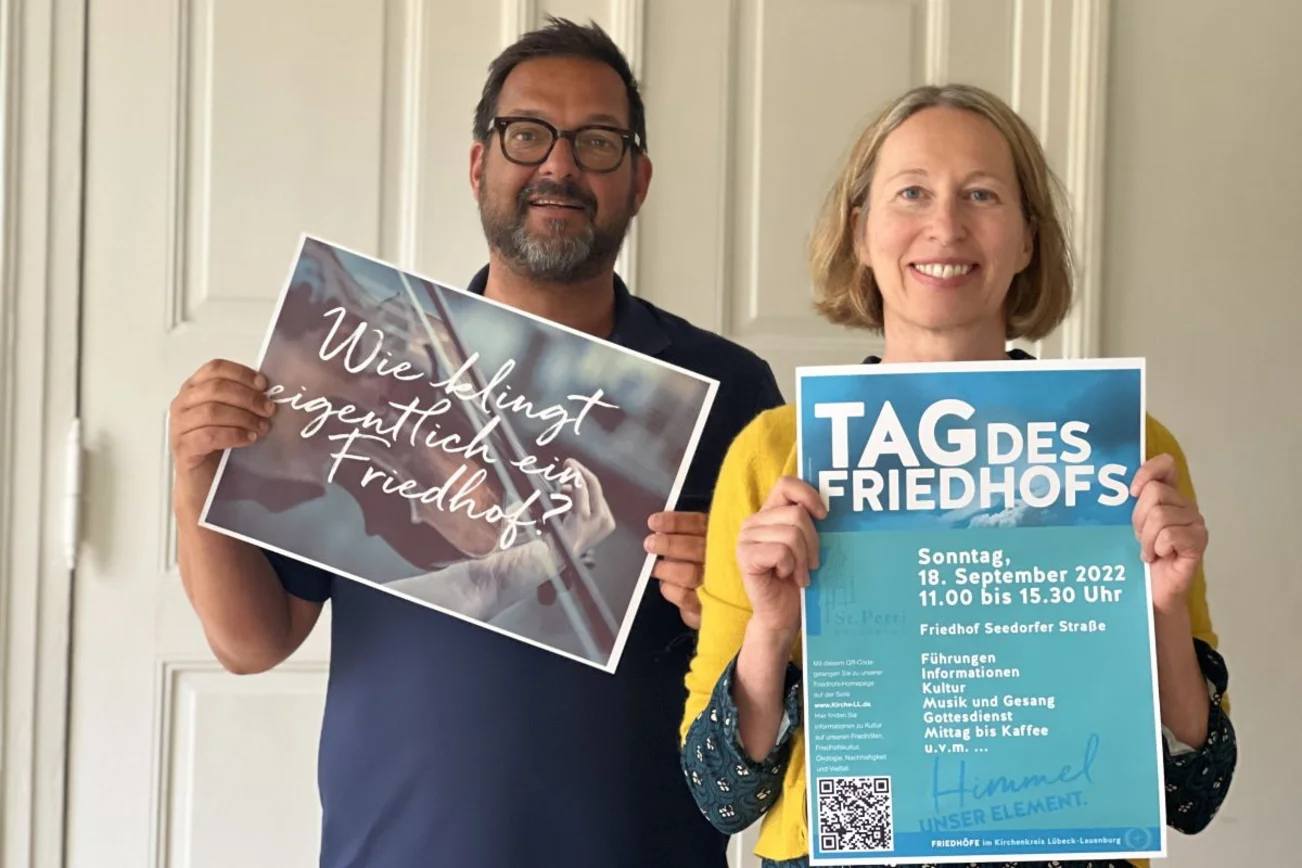 Mann und Frau mit Plakaten zum "Tag des Friedhofs"