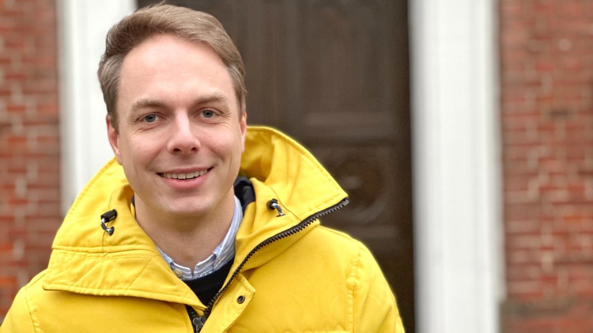 Ein Mann in gelber Jacke steht vor einer Kirche.