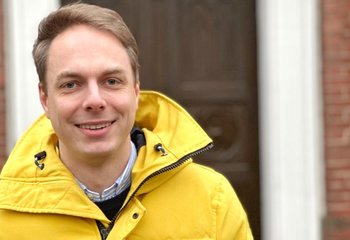 Ein Mann in gelber Jacke steht vor einer Kirche. - Copyright: KKLL
