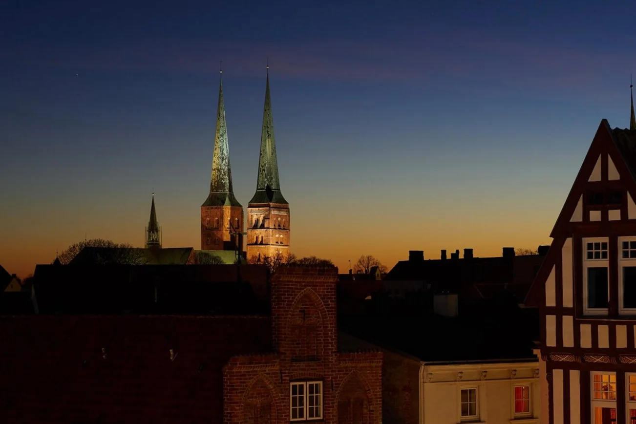 Die Türme des Doms zu Lübeck werden in der Abenddämmerung von künstlichem Licht angestrahlt.