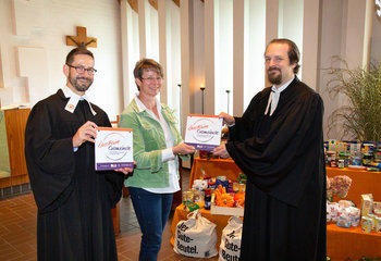 Drei Personen stehen mit einem Schild lächelnd in einer Kirche. - Copyright: Elisabeth von Schönberg