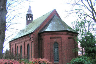 Die Süd-West-Ansicht der Friedhofskapelle Berkenthin, umgeben von Bäumen und Pflanzen