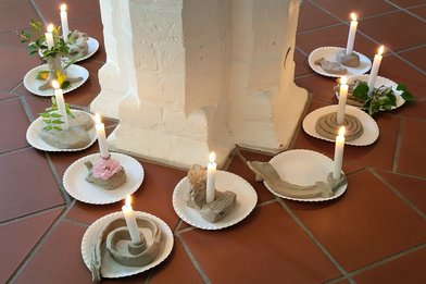 Kerzen auf Tellern stehen um eine Säule - Copyright: Ev. Frauenwerk
