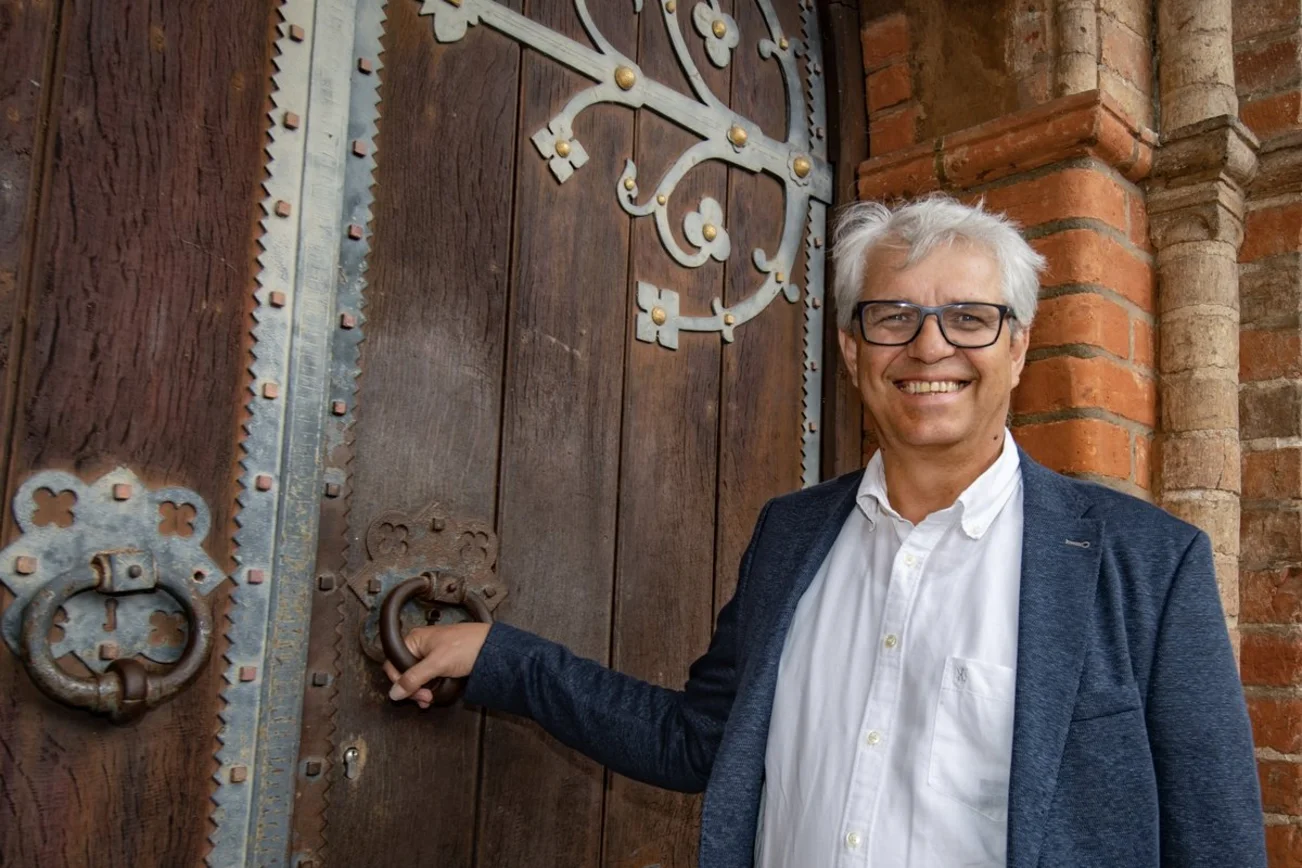 Ein Mann steht lächelnd an einer Tür. 