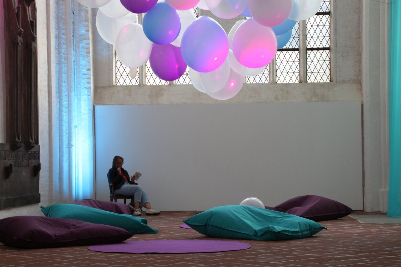 Sitzkissen in einer Kirche, darüber beleuchtete Luftballons