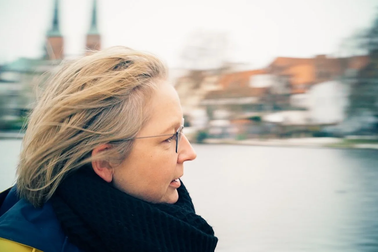 Eine Frau im seitlichen Profil, im Hintergrund die Türme des Lübecker Doms.
