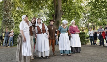 Eine Gruppe mit historischen Kostümen steht auf einem Friedhof