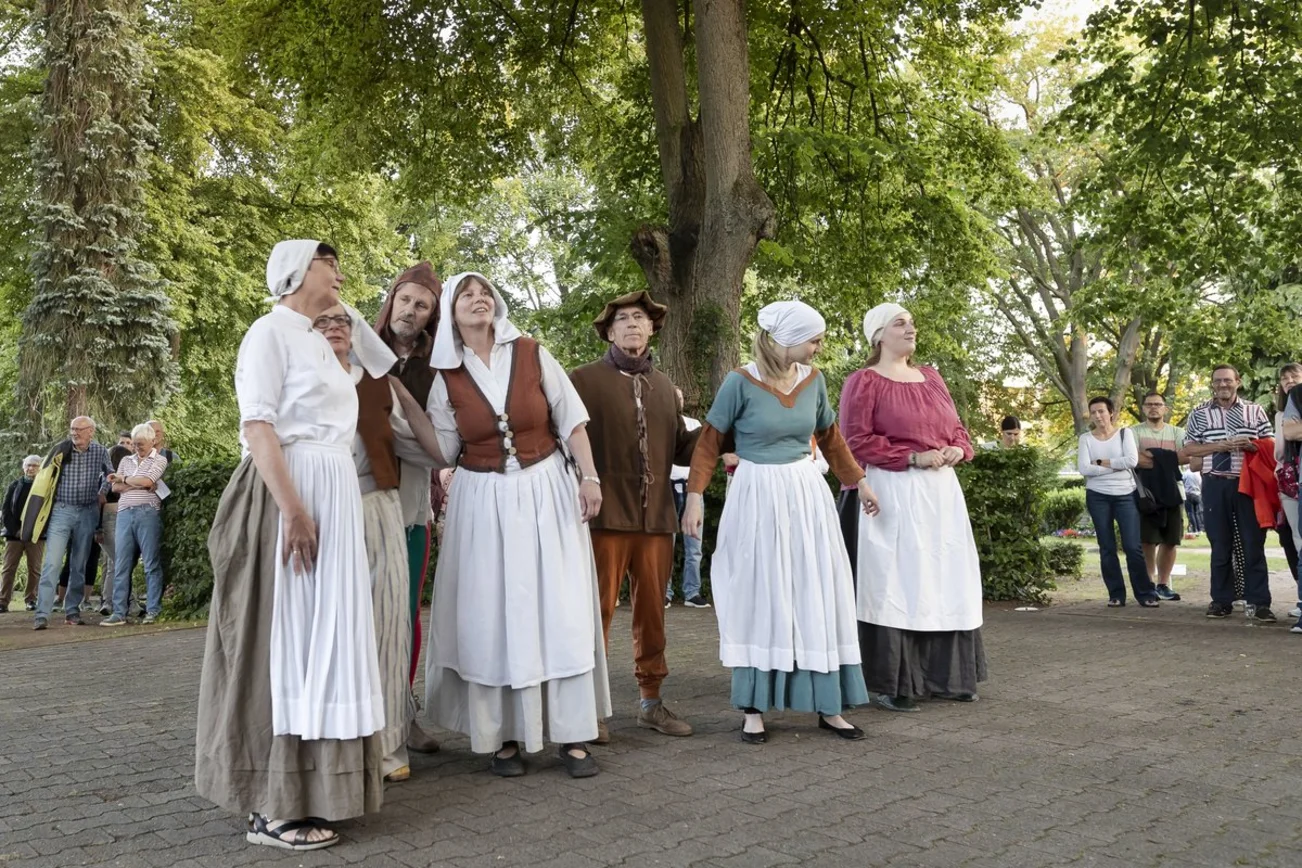 Eine Gruppe mit historischen Kostümen steht auf einem Friedhof