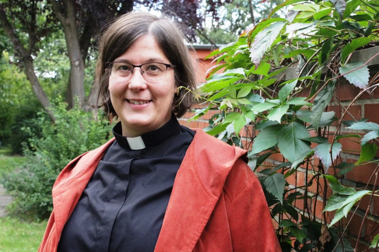 Eine Frau mit Brille, im Hintergrund eine Backsteinmauer mit Weinranken.