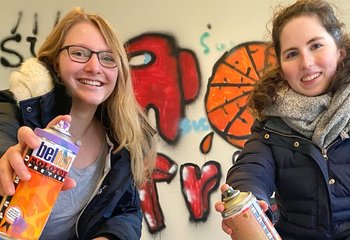 Zwei junge Frauen lächeln mit einer Farbsprühflasche in der Hand in die Kamera. - Copyright: Bastian Modrow