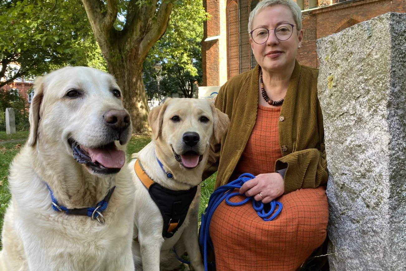 Eine Frau und zwei Hunde sitzen vor einer Kirche
