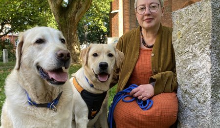 Eine Frau und zwei Hunde sitzen vor einer Kirche