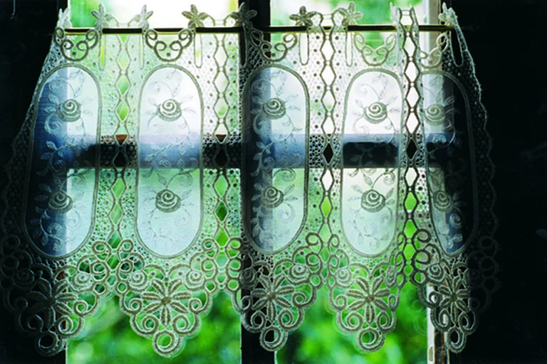 Ein Fenster mit Gardine und Blick Richtung Helligkeit und verschwommenen grünem Garten symbolisiert den Ewigkeitssonntag