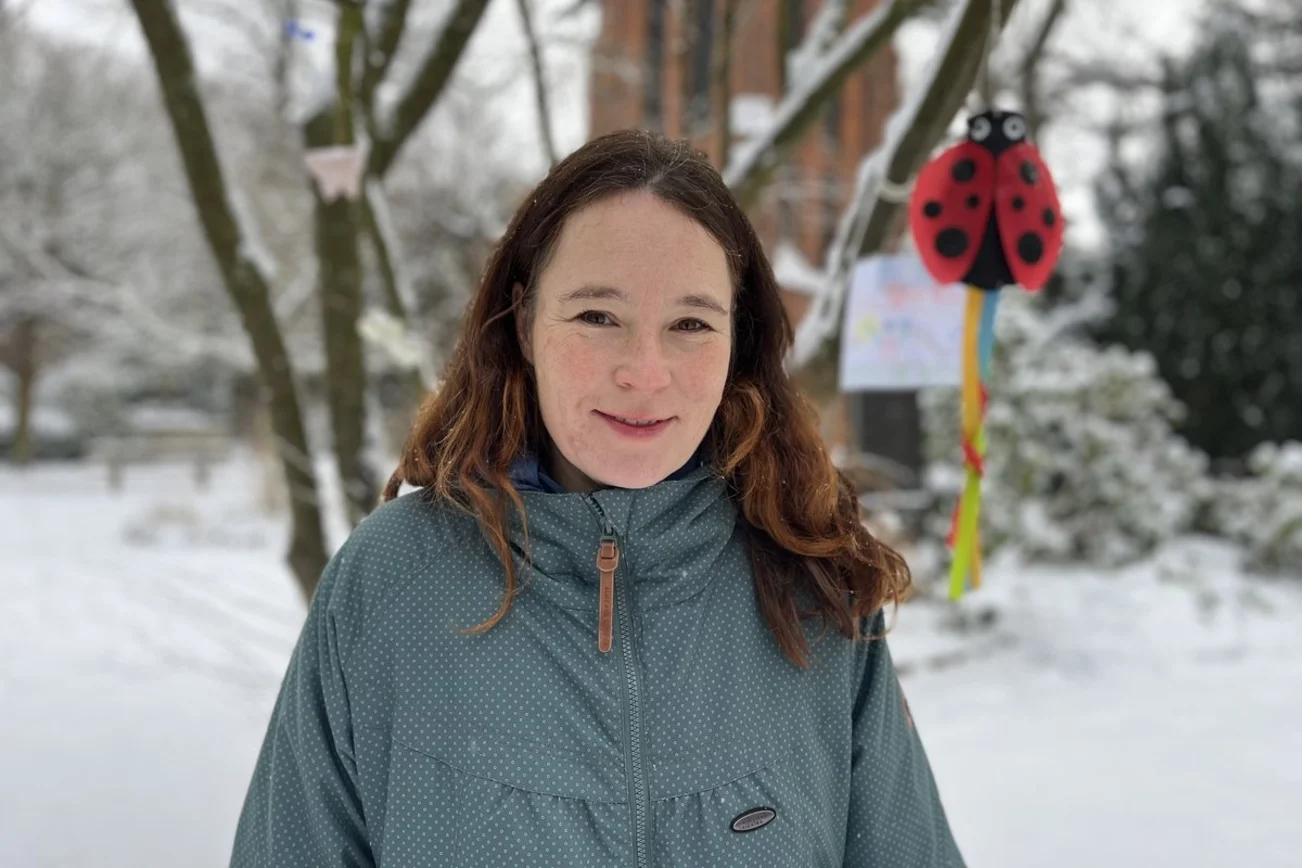 Eine Frau mit langen Haaren steht auf einem verschneiten Friedhof