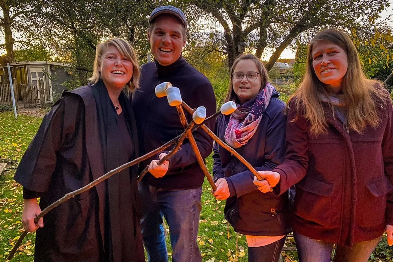 Personen stehen lächelnd im Garten mit Marshmallows.