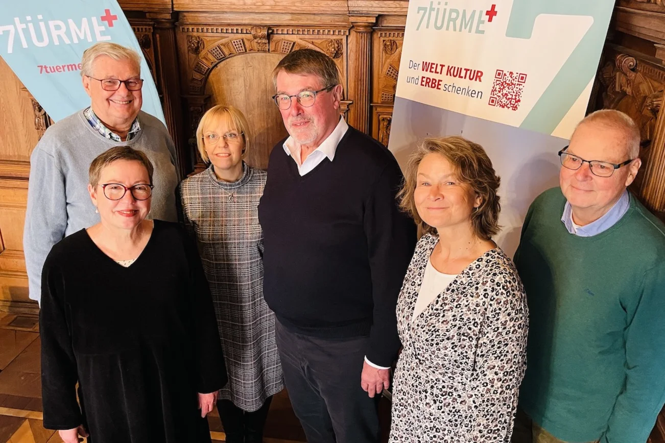 Eine Frau und zwei Männer der Wessel Stiftungen stehen mit der Pröpstin Petra Kallies und Referentin Heike Reimann von 7Türme+ vor einem Rollup und einer Beachflag des Projektes. 