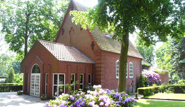 Friedhofskapelle St.-Lorenz Travemünde - Copyright: contactImageCopyright_stringS Friedhofskapelle St.-Lorenz Travemünde mit blühenden lila Rhododendron-Pflanzen - Copyright: contactImageCopyright_stringS