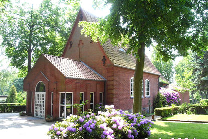 Friedhofskapelle St.-Lorenz Travemünde mit blühenden lila Rhododendron-Pflanzen