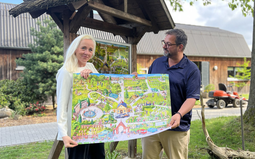 Zwei Personen stehe mit einem Plakat vor einem Schaukasten