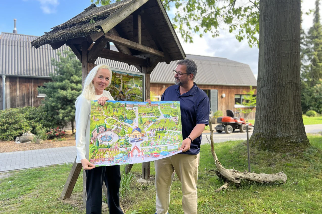 Zwei Personen stehe mit einem Plakat vor einem Schaukasten