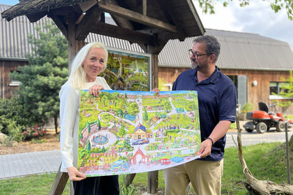 Zwei Personen stehe mit einem Plakat vor einem Schaukasten - Copyright: KKLL