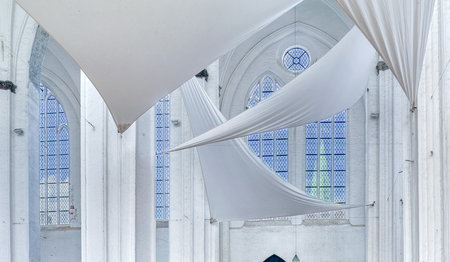 Weiße Segel sind im Inneren von St. Petri gespannt und die weißen Säulen geben einen wunderschönen Kontrast zu den Kirchenfenstern im Hintergrund. Der Himmel leuchtet im schönen blau und  St. Marien ist durch das rechte Fenster zu sehen.