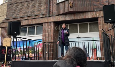 Eine Frau steht auf einem Podium und hät eine Rede.