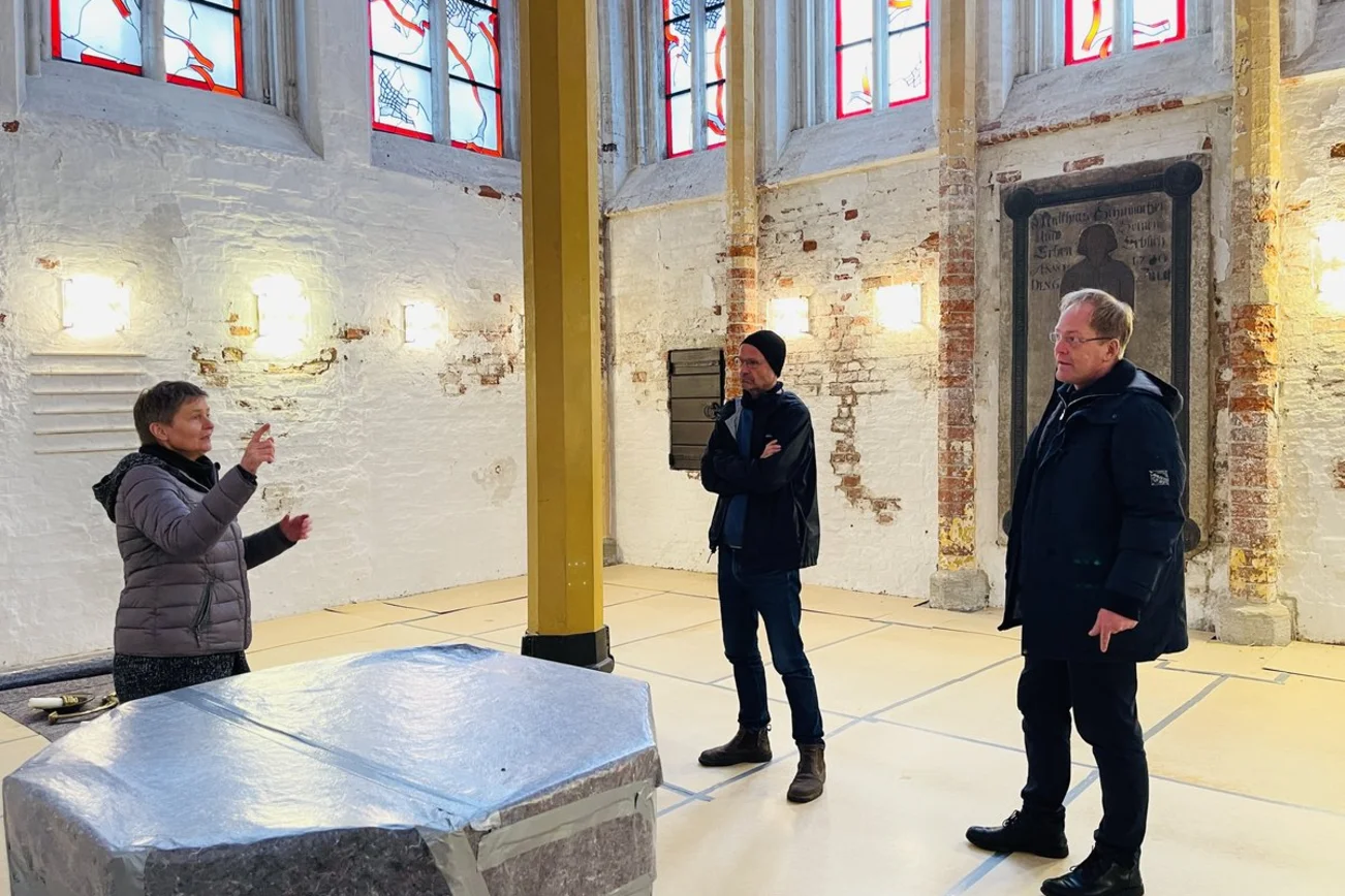 Drei Personen stehen in einer Kirche